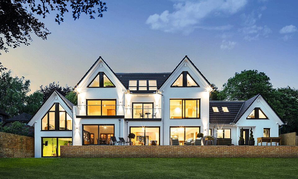 Haus mit großer Fensterfront in Abendstimmung