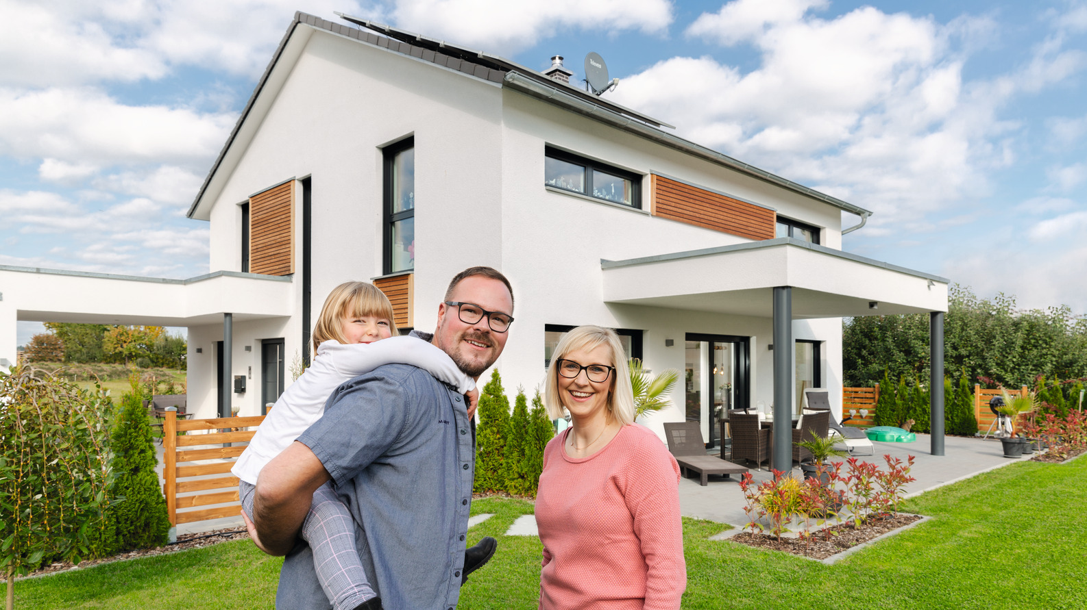 glückliche Familie vor ihren Einfamilienhaus von WeberHaus