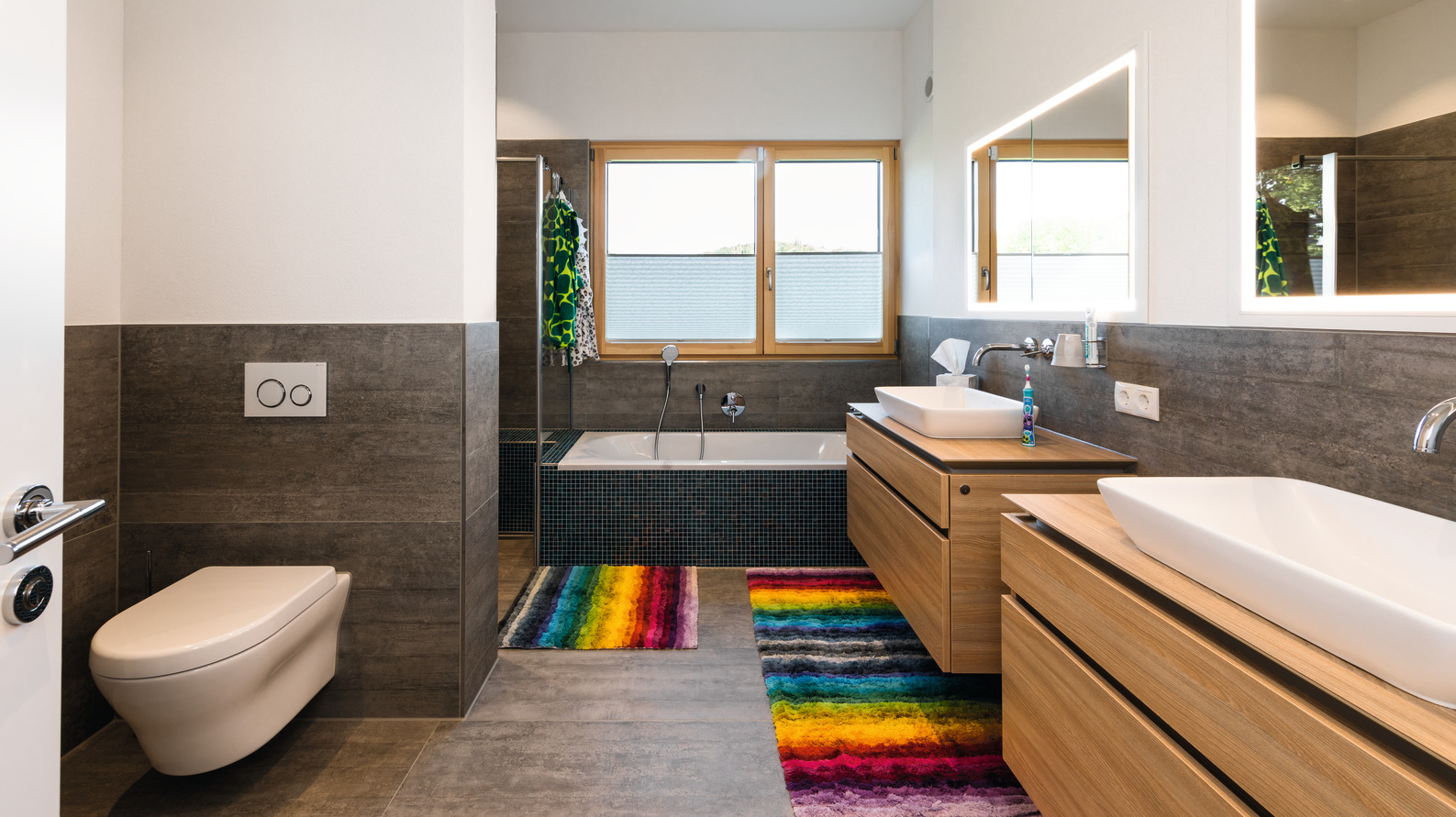 Badezimmer mit Badewanne und bunten Teppichen Badezimmer mit Badewanne und bunten Teppichen