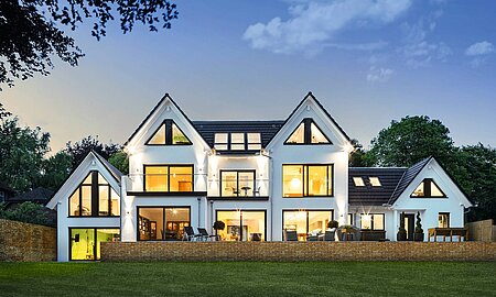 Haus mit großer Fensterfront in Abendstimmung