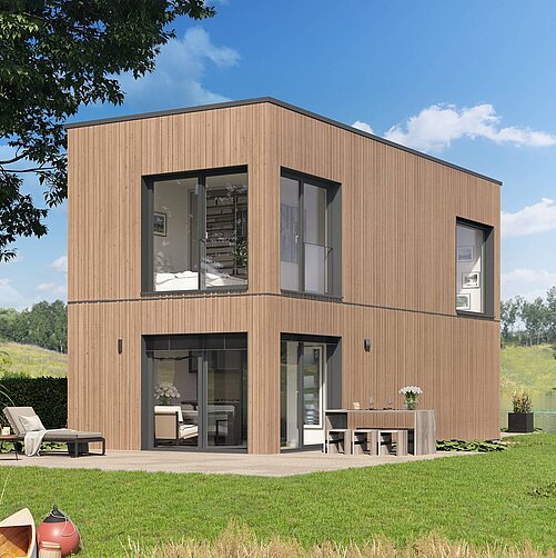 Ein modernes, zweigeschossiges Holzhaus mit großen Fenstern steht in einer grünen Umgebung. Vor dem Haus befindet sich eine Terrasse mit Gartenmöbeln und einem Tisch. Im Hintergrund sind Bäume und Wasser zu sehen, was eine ruhige, naturnahe Atmosphäre erzeugt.