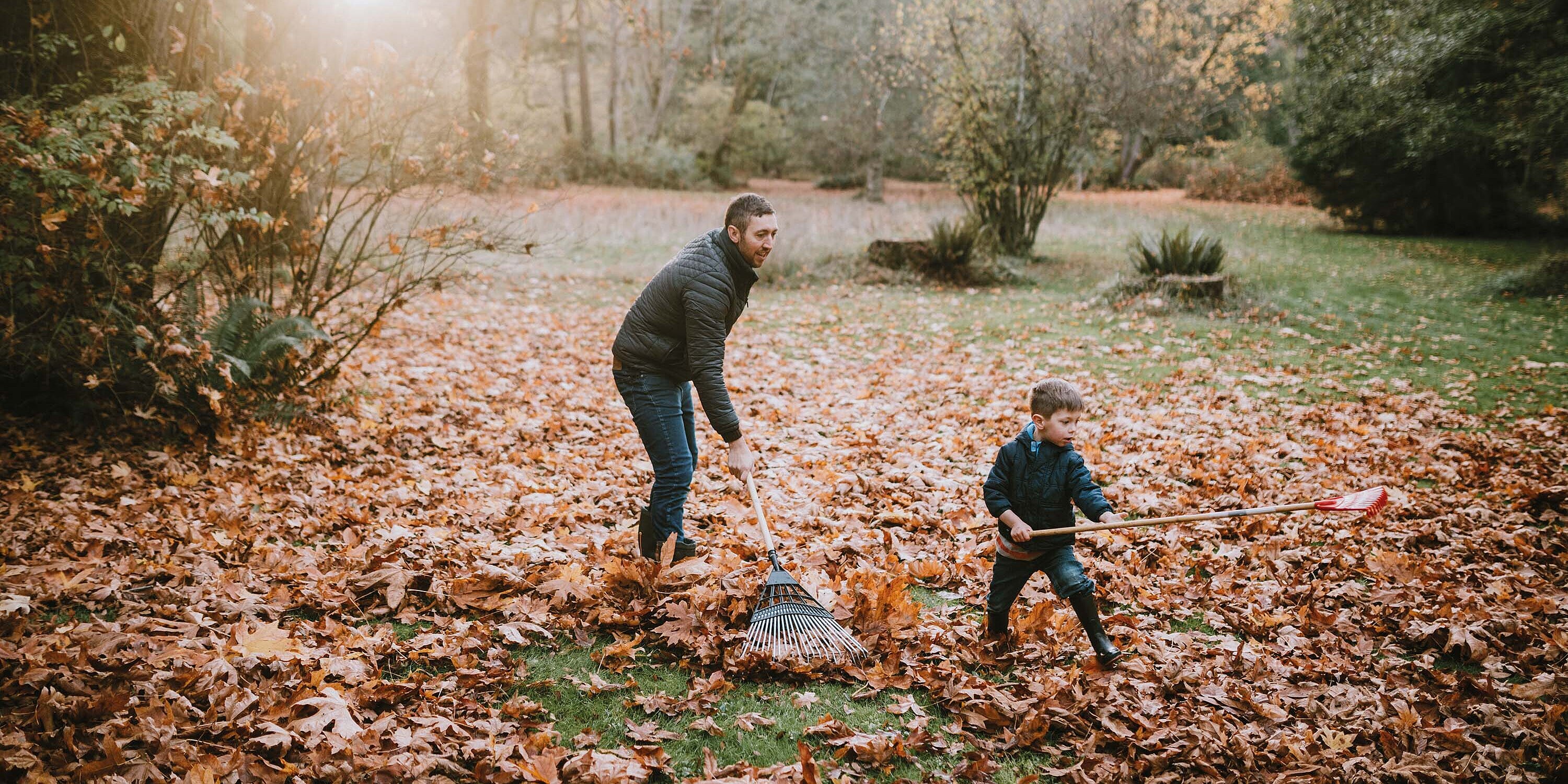 Vater und Sohn beim Laubharken