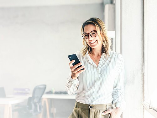 Frau sieht auf Smartphone und lächelt