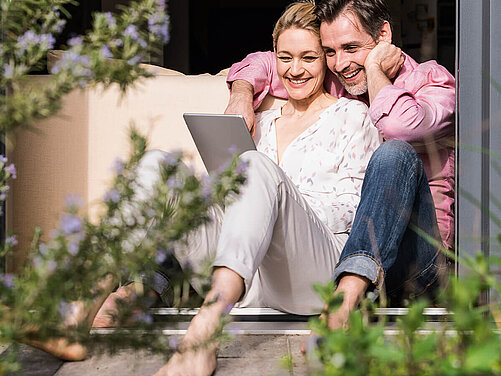 Paar sitzt auf Terrasse mit einem Tablet