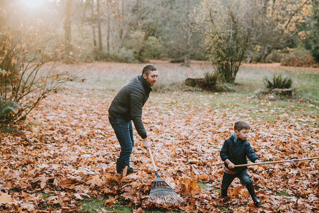 Vater und Sohn beim Laubharken