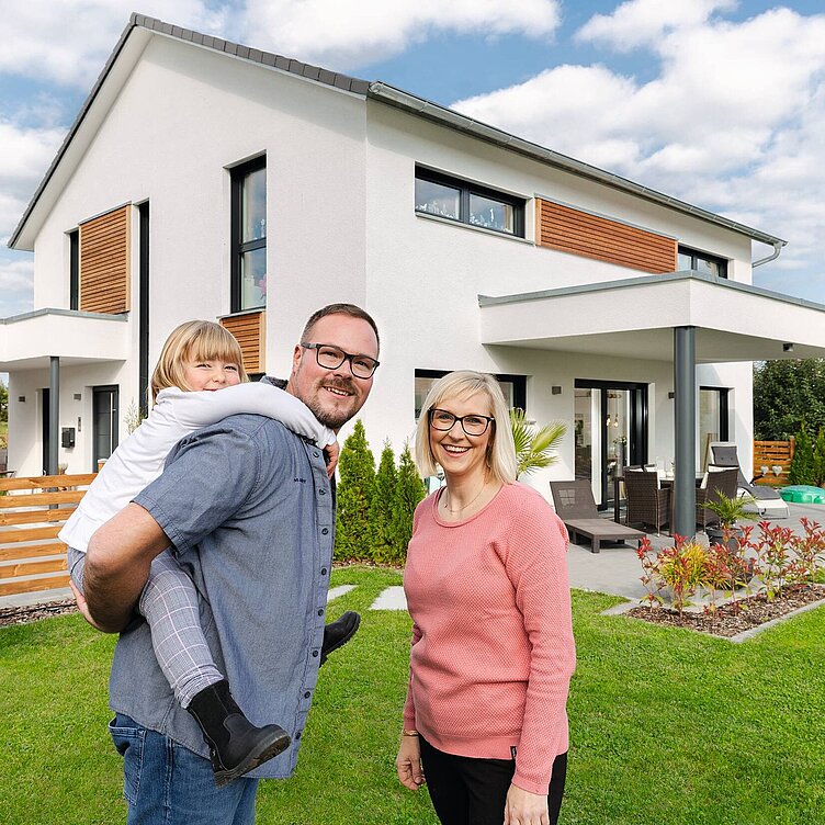 glückliche Familie vor ihren Einfamilienhaus von WeberHaus